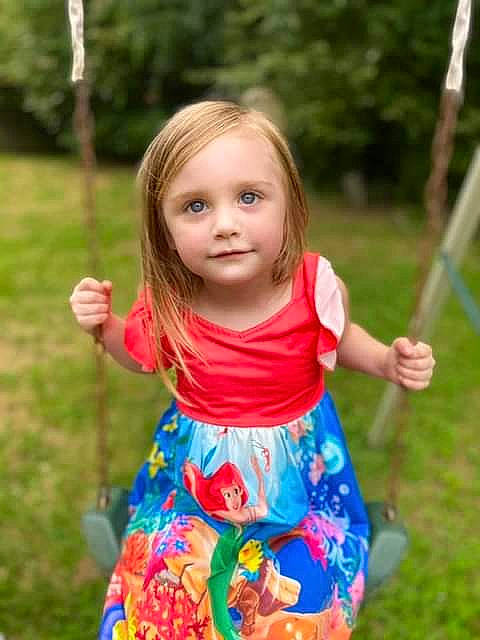 Danielle is registered to the contest to win money with this photo: baby_toddler_clothing, child, dress, facial_expression, fun, grass, hair, hairstyle, happy, leaf, leisure, nature, people, people_in_nature, person, plant, sleeve, standing, summer, toddler