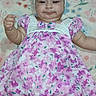 adorable, baby, blanket, child, chubby_cheeks, cute, dress, floral, flower, footwear, happy, headband, indoor, infant, infant_clothing, lying_down, person, pink, smile, soft_texture