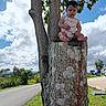 Jenibeth is registered to the contest to win money with this photo: baby, child, tree_stump, tree, outdoor, sky, clouds, road, grass, person, nature, greenery, sunlight, daytime, cute, infant, sitting, leaves, footpath, scenery