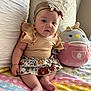 baby, infant, child, headband, bow, skirt, ruffles, plush_toy, stuffed_animal, blanket, patterned_clothing, pastel_colors, sitting, indoors, cute, soft_lighting, chubby_cheeks, foot, hand, couch