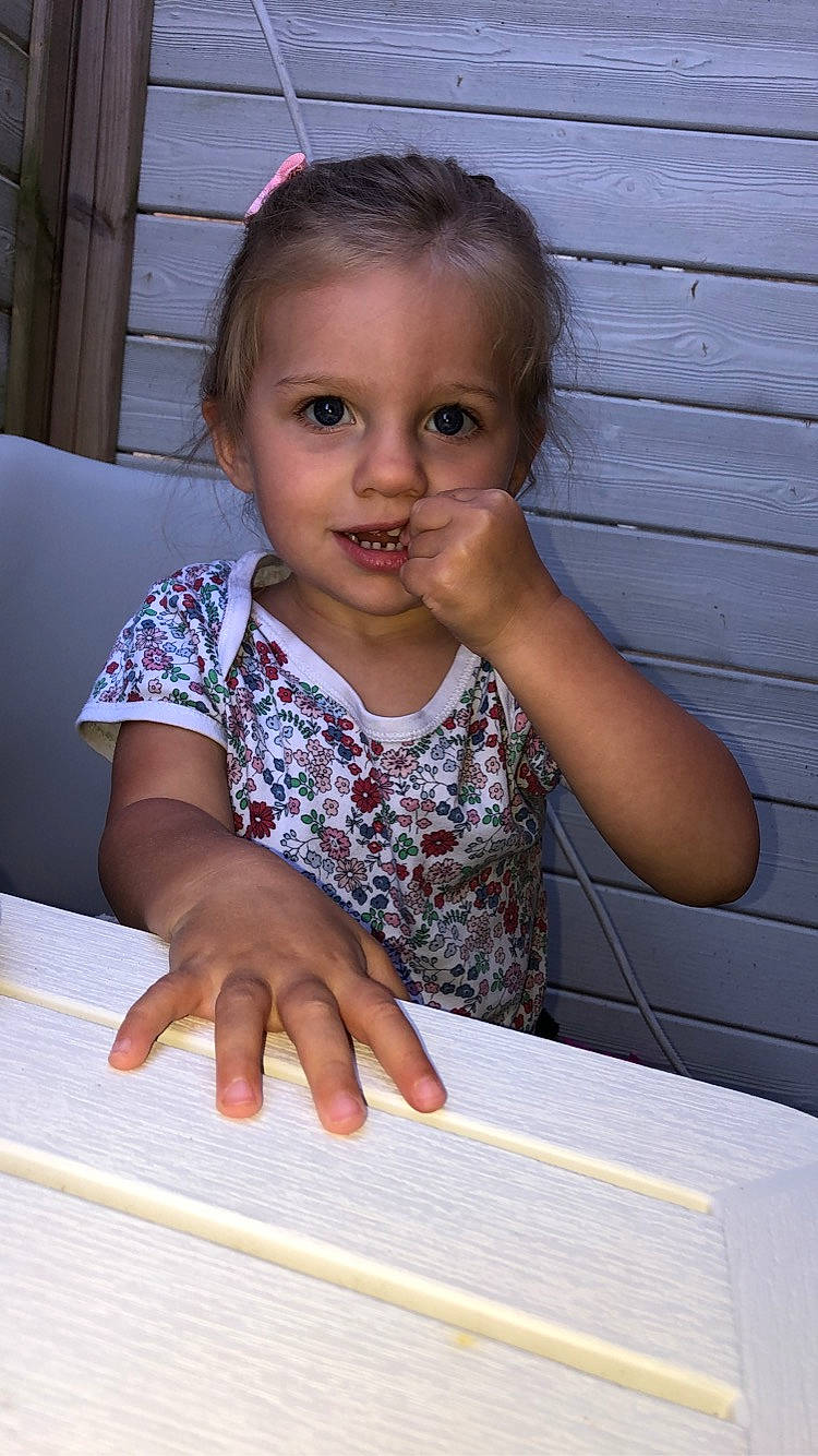 Julia Fouche participe au concours pour gagner de l'argent avec cette photo : baby_toddler_clothing, cheek, child, desk, face, finger, flooring, fun, happy, iris, nail, office_supplies, person, sitting, smile, table, thumb, toddler, wood, writing