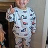 Andrew is registered to the contest to win money with this photo: child, clothing, construction_vehicles, door, dump_truck, excavator, floor, full_body, happy, home, indoors, pajamas, portrait, smiling, sneakers, standing, thumbs_up, toddler, toy_trucks, wall