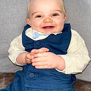 Milann participe au concours pour gagner de l'argent avec cette photo : baby, blue_vest, child, clasped_hands, clothing, cream_shirt, cute, expression, eyes, face, hands, happy, indoor, infant, person, portrait, seated, skin, smiling, young