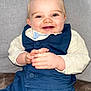 baby, blue_vest, child, clasped_hands, clothing, cream_shirt, cute, expression, eyes, face, hands, happy, indoor, infant, person, portrait, seated, skin, smiling, young