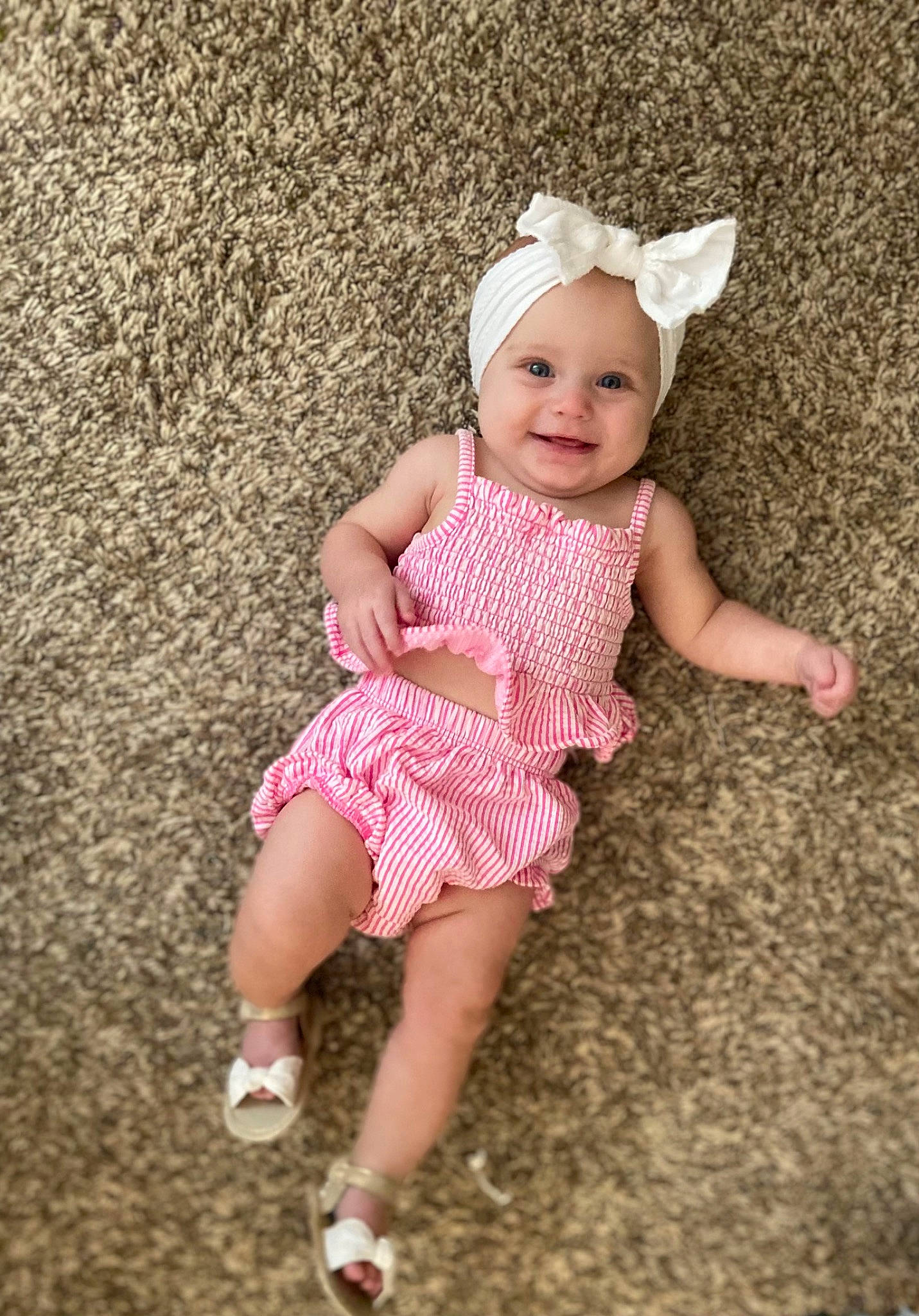 Aubrey is registered to the contest to win money with this photo: arm, baby, baby_toddler_clothing, day_dress, dress, eye, foot, fun, grass, happy, headwear, human_leg, joy, magenta, pattern, person, pink, sandal, sitting, skin