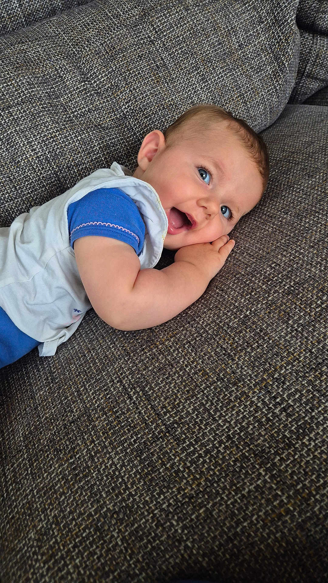 Aimée a rejoint le concours — aidez-le/la à gagner de superbes lots ! baby, blue_eyes, smiling, lying_down, couch, textured_fabric, infant, happy, child, close_up, casual_clothing, toddler, indoor, portrait, skin, face, hand, cute, young_child, relaxing