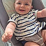 baby, child, smiling, happy, face, arm, legs, striped_shirt, baby_rocker, cushion, indoor, person, closeup, cute, infant, skin, blue_eyes, short_hair, happy_expression, reaching_hand