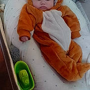 Mael participe au concours pour gagner de l'argent avec cette photo : baby, infant, onesie, animal_costume, orange, cushion, star_pattern, soft_toys, stuffed_animals, bottle, lying_down, indoors, cute, chubby_cheeks, face, headwear, child, comfort, plush, person