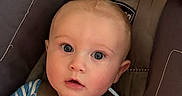 Raine is registered to the contest to win money with this photo: baby, child, infant, car_seat, harness, portrait, face, blue_eyes, wide_eyed, sitting, striped_shirt, clothing, indoor, vehicle, safety, close_up, looking_at_camera, head, photography, cute