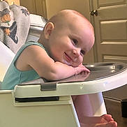 Raine joined the competition — help win amazing prizes! baby, child, infant, smiling, happy, portrait, high_chair, tray, indoor, home, green_clothing, blanket, door, furniture, sitting, leaning, face, hands, bare_feet, warm_lighting