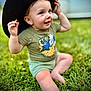 animal_print, baby, child, cute, feet, grass, green, hands, happy, hat, nature, outdoor, playful, portrait, shirt, shorts, sitting, smiling, sunlight, toddler