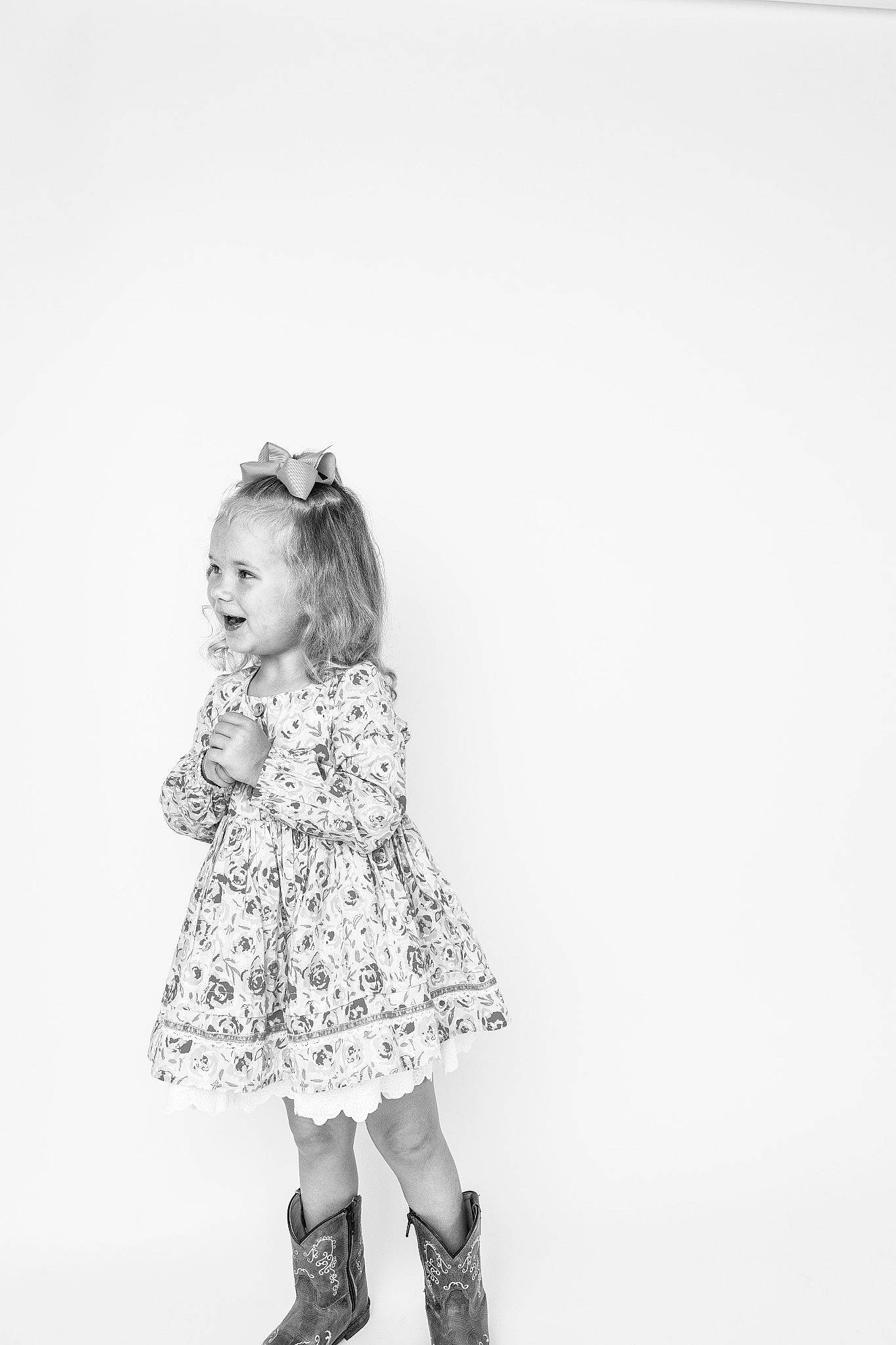 Callie is registered to the contest to win money with this photo: arm, baby_toddler_clothing, day_dress, dress, eye, fashion_design, gesture, hand, happy, head, human_body, human_leg, monochrome, monochrome_photography, one_piece_garment, pattern, person, sleeve, sock, toddler