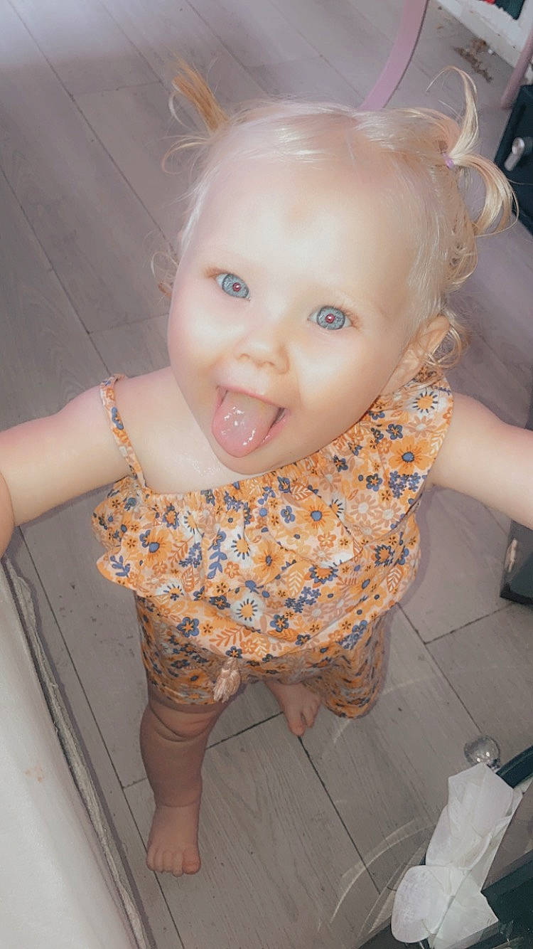 Amelia-rose is registered to the contest to win money with this photo: baby, baby_toddler_clothing, cheek, dress, finger, flash_photography, floor, flooring, happy, iris, joint, lip, mouth, nose, pattern, person, pink, skin, smile, standing