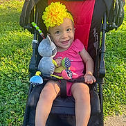 Luismar Leal Palan joined the competition — help win amazing prizes! baby, child, stroller, toy, headband, yellow_flower, pink_clothing, smile, happy, outdoor, grass, sunlight, footwear, sitting, infant, playful, cute, person, daylight, park