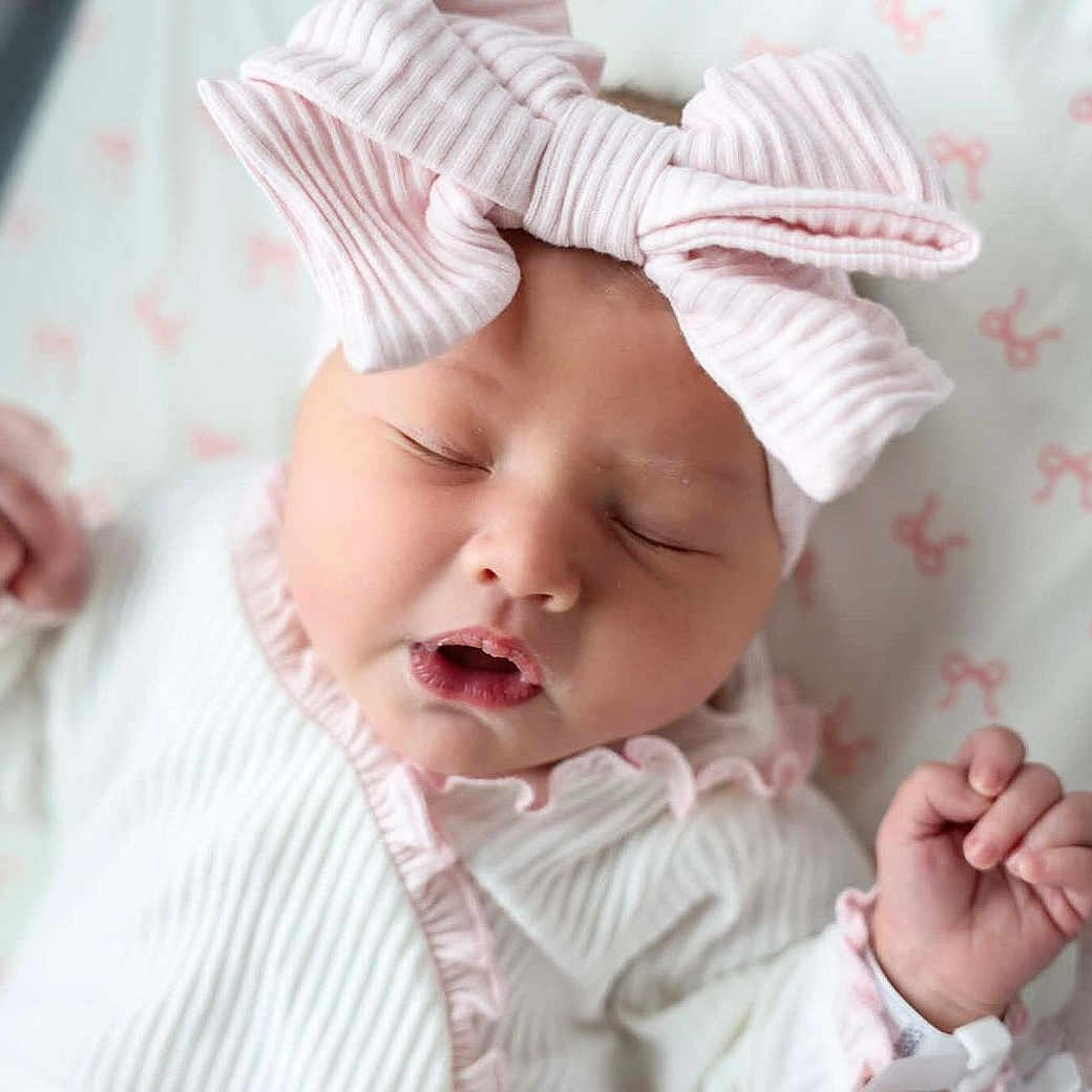 Oakley joined the competition — help win amazing prizes! baby, newborn, sleeping, portrait, pink, bow, headband, onesie, infant, face, hands, closed_eyes, peaceful, cute, nursery, blanket, crib, indoors, closeup, photography
