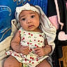 adorable, baby, blanket, blue_background, bow, car_seat, cherry_pattern, child, clothing, curious, cute, dress, headband, indoors, infant, person, portrait, sitting, soft_texture, young