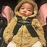 baby, child, car_seat, teddy_bear_hoodie, fluffy_clothing, straps, pink_padding, black_padding, infant, cute, warm, seated, portrait, face, safety_harness, young_child, adorable, comfort, casual, indoors