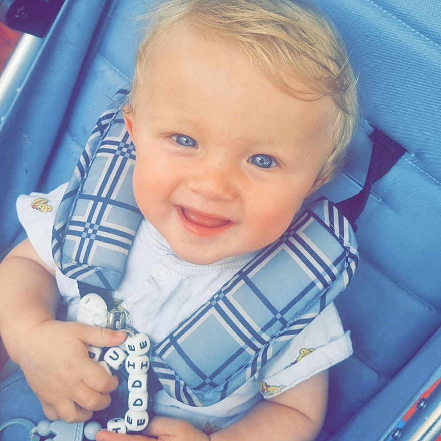 Teddie-Blu is registered to the contest to win money with this photo: baby, baby_clothes, blonde, blue, blue_eyes, child, clothing, cute, face, hand, happy, head, infant, outdoor, person, portrait, seatbelt, smiling, stroller, toy