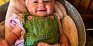 Piper is registered to the contest to win money with this photo: baby, infant, smiling, headband, bow, green_overalls, pink_bow, blanket, basket, wooden_background, cute, child, portrait, happy, indoor, soft_texture, comfortable, clothing, person, skin