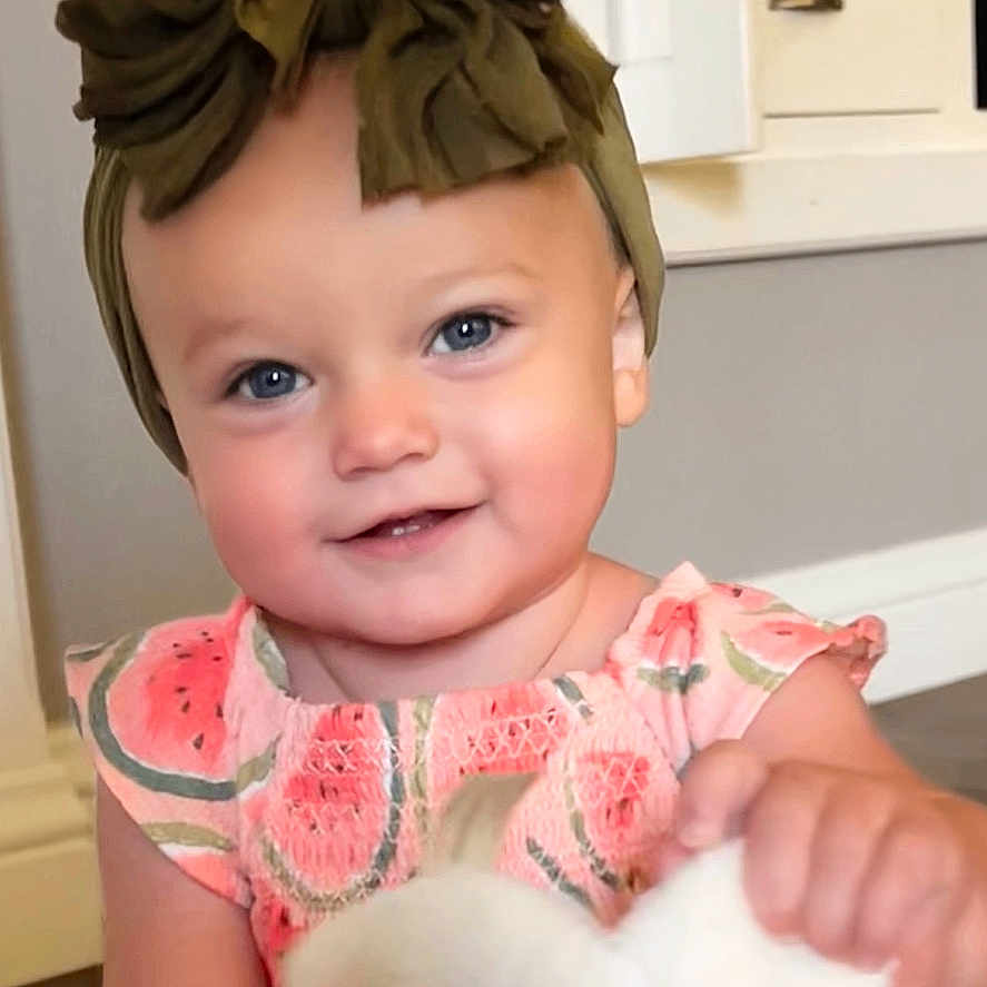 Calah Ray joined the competition — help win amazing prizes! baby, blue_eyes, bow, child, cuteness, dress, floor, green, happy, headband, holding, indoor, infant, patterned_clothing, pink, portrait, smile, stuffed_animal, toddler, toy