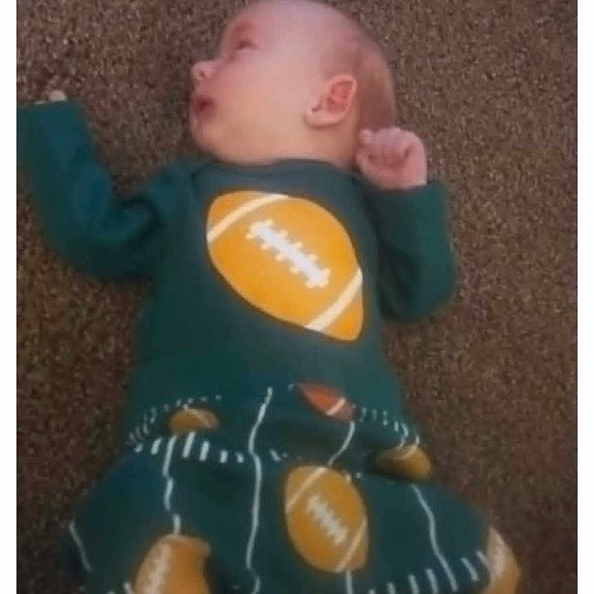 Leason joined the competition — help win amazing prizes! baby, infant, carpet, football, clothing, green_outfit, pattern, lying_down, child, cute, small, soft_lighting, indoor, portrait, casual, resting, young, person, toddler, sleepy