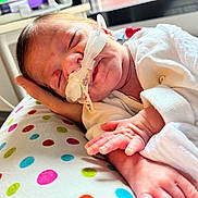 Ilham participe au concours pour gagner de l'argent avec cette photo : newborn, baby, infant, medical_tube, hospital, blanket, hand, polka_dot, resting, sleeping, cute, skin, clothing, bed, care, child, small, indoors, comfort, patient