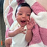 Mikiyo is registered to the contest to win money with this photo: baby, infant, smiling, hand, face, blanket, towel, white_clothing, cute, happy, newborn, skin, portrait, indoors, person, pink, white, soft_texture, lying_down, cozy