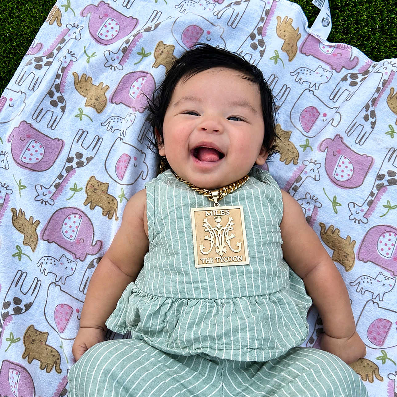 Mikiyo joined the competition — help win amazing prizes! baby, child, smiling, green_striped_outfit, necklace, gold_chain, blanket, animal_print, grass, outdoor, cute, happy, infant, portrait, person, clothing, lying_down, playful, head, face