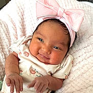 Solar is registered to the contest to win money with this photo: baby, infant, smile, pink_bow, headband, blanket, cute, newborn, clothing, fruit_prints, soft_texture, lying_down, chubby_cheeks, happy, portrait, child, human, skin, hand, face