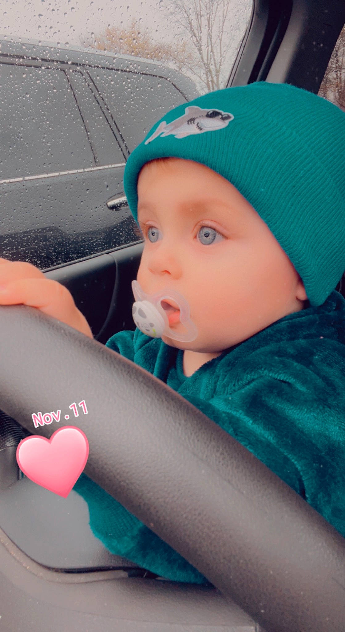 Michael is registered to the contest to win money with this photo: automotive_design, baby, baby_products, baby_toddler_clothing, baseball_cap, blue, cap, car_seat, child, electric_blue, fun, headwear, human_body, person, personal_protective_equipment, product, recreation, skin, steering_wheel, toddler