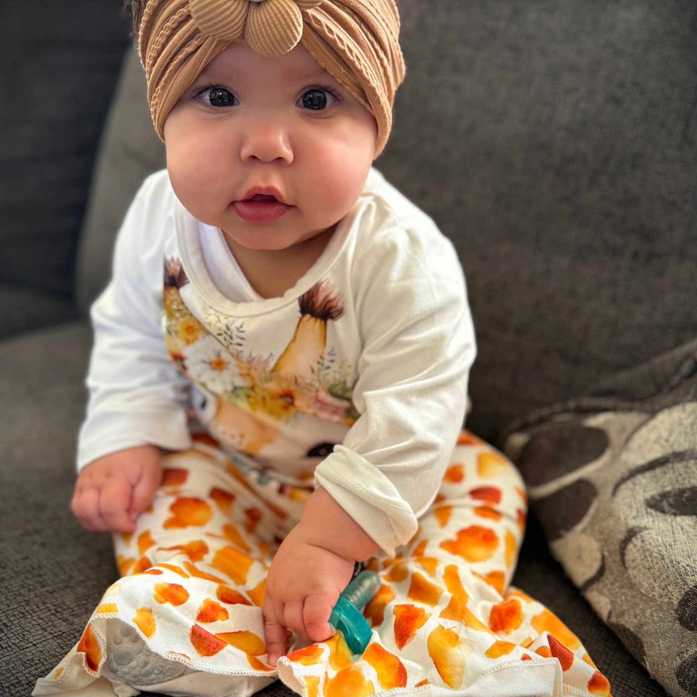 Melani Farilien is registered to the contest to win money with this photo: baby, blanket, bodypart, cap, clothing, couch, dress, face, finger, formalwear, furniture, hand, happy, hat, head, person, photography, portrait, sitting, smile