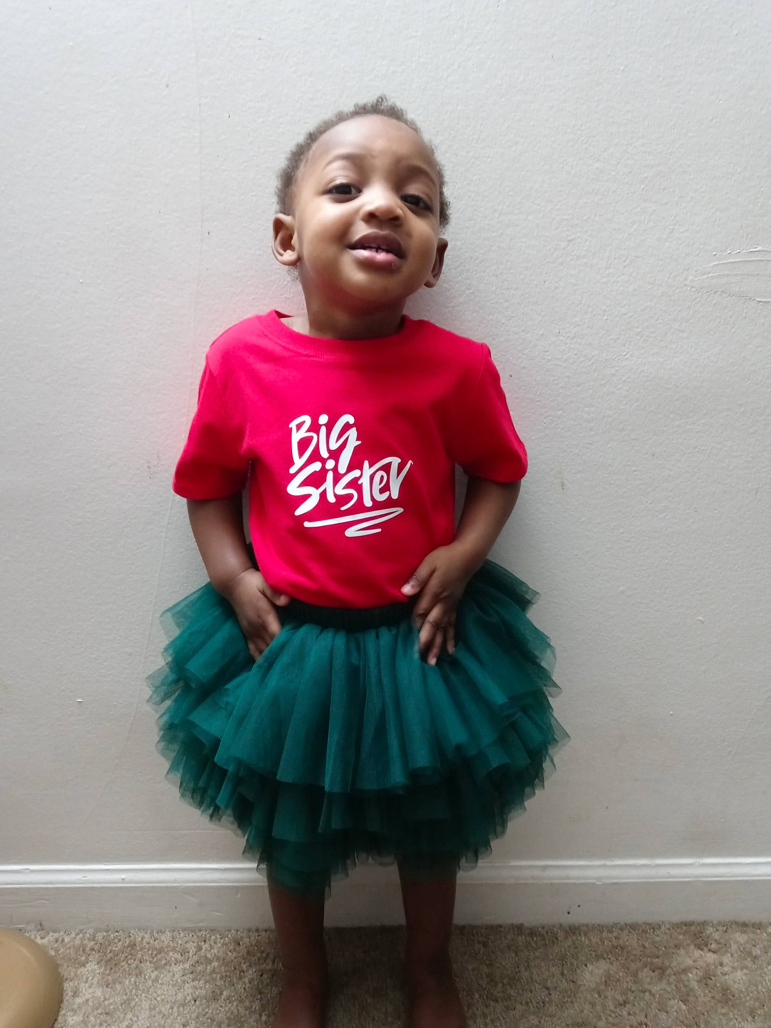 Amara is registered to the contest to win money with this photo: arm, baby_toddler_clothing, eye, face, hair, happy, head, human_body, joint, neck, person, pink, shoulder, skin, sleeve, smile, standing, t_shirt, toddler, trunk