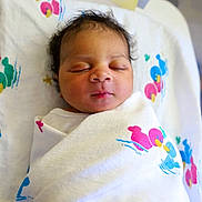 Majier is registered to the contest to win money with this photo: newborn, baby, sleeping, swaddled, blanket, duck_pattern, hospital_bassinet, infant, closeup, face, peaceful, curly_hair, soft_light, indoors, child, cute, resting, portrait, wrapped, toddler