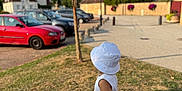 Idris a rejoint le concours — aidez-le/la à gagner de superbes lots ! child, hat, summer_clothing, grass, tree, cars, village, building, sky, sunlight, outdoor, side_view, footwear, road, nature, daytime, casual, young_child, vacation, relaxation