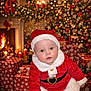 baby, child, santa_claus_costume, christmas_tree, fireplace, presents, holiday, festive, red_clothing, white_fur_trim, indoors, decorations, candles, warm_light, cute, smiling, holiday_season, christmas, seasonal, celebration
