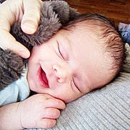 John is registered to the contest to win money with this photo: architecture, baby, blanket, bodypart, building, clothing, cushion, face, finger, glove, hand, happy, head, homedecor, laughing, newborn, person, photography, portrait, sleeping