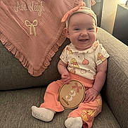 Ava Leigh joined the competition — help win amazing prizes! baby, infant, child, smiling, sitting, couch, indoor, portrait, headband, bow, blanket, ruffles, peach_clothing, patterned_shirt, pants, socks, milestone_plaque, toy, home, happy