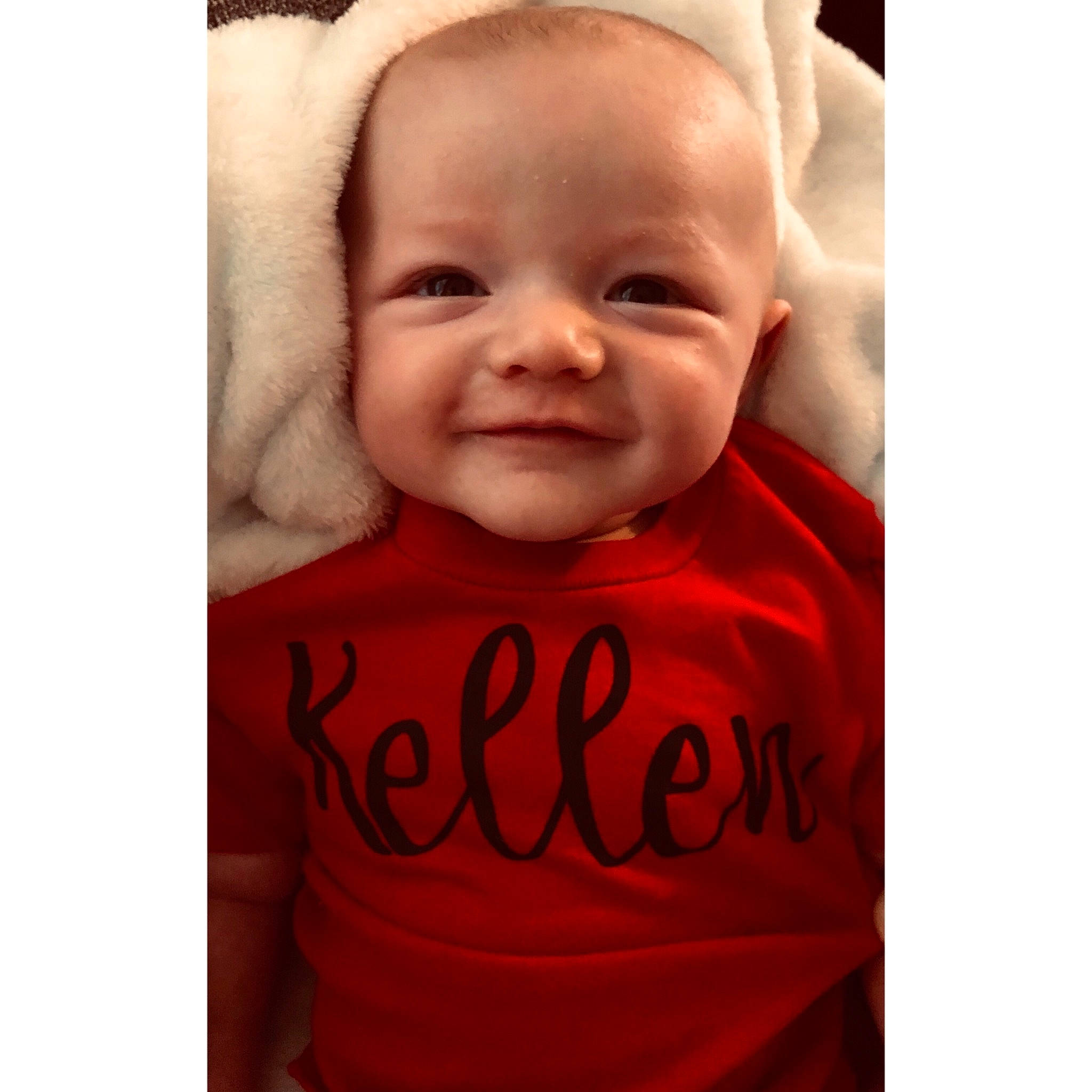 Kellen is registered to the contest to win money with this photo: baby, baby_laughing, cheek, child, cool, face, facial_expression, happy, head, hood, joy, laugh, lip, nose, outerwear, person, product, red, sleeve, smile