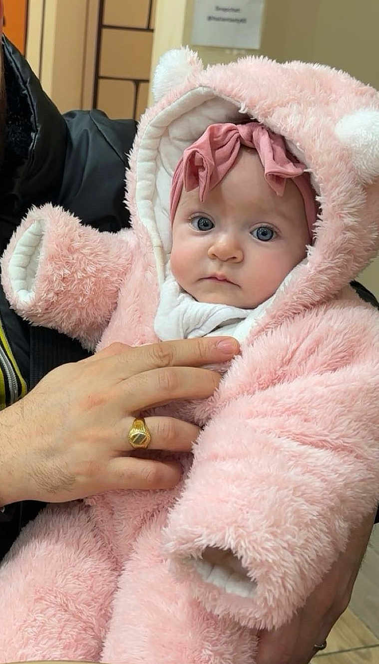 Ines a rejoint le concours — aidez-le/la à gagner de superbes lots ! baby, child, infant, pink, fluffy, hood, bear_ears, headband, blue_eyes, hand, ring, clothing, indoor, portrait, person, cute, warm, soft_texture, holding, looking