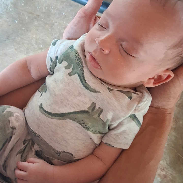 Christopher joined the competition — help win amazing prizes! baby, sleeping, infant, dinosaur_print, clothing, arms, hand, person, portrait, casual, comfort, nap, peaceful, indoor, human, skin, head, face, young_child, rest