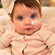 Jaylee is registered to the contest to win money with this photo: baby, infant, child, portrait, close_up, wide_eyed, smiling, pink_outfit, headband, bow, bandage, face, eyes, indoors, blanket, soft_lighting, sitting, baby_clothing, cozy, photography