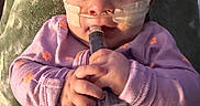 Jaylee joined the competition — help win amazing prizes! baby, blanket, child, cozy, curiosity, face, hands, healthcare, indoor, infant, medical_tape, nasal_tube, orange_flowers, person, portrait, purple_onesie, soft_lighting, syringe, toddler, wide_eyes