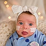 Jaylee joined the competition — help win amazing prizes! baby, infant, bow_headband, blue_outfit, smiley_face, nasal_oxygen_tube, tape, closeup, portrait, cute, wide_eyes, soft_background, bokeh, blanket, indoors, child, newborn, expression, wearing, headwear