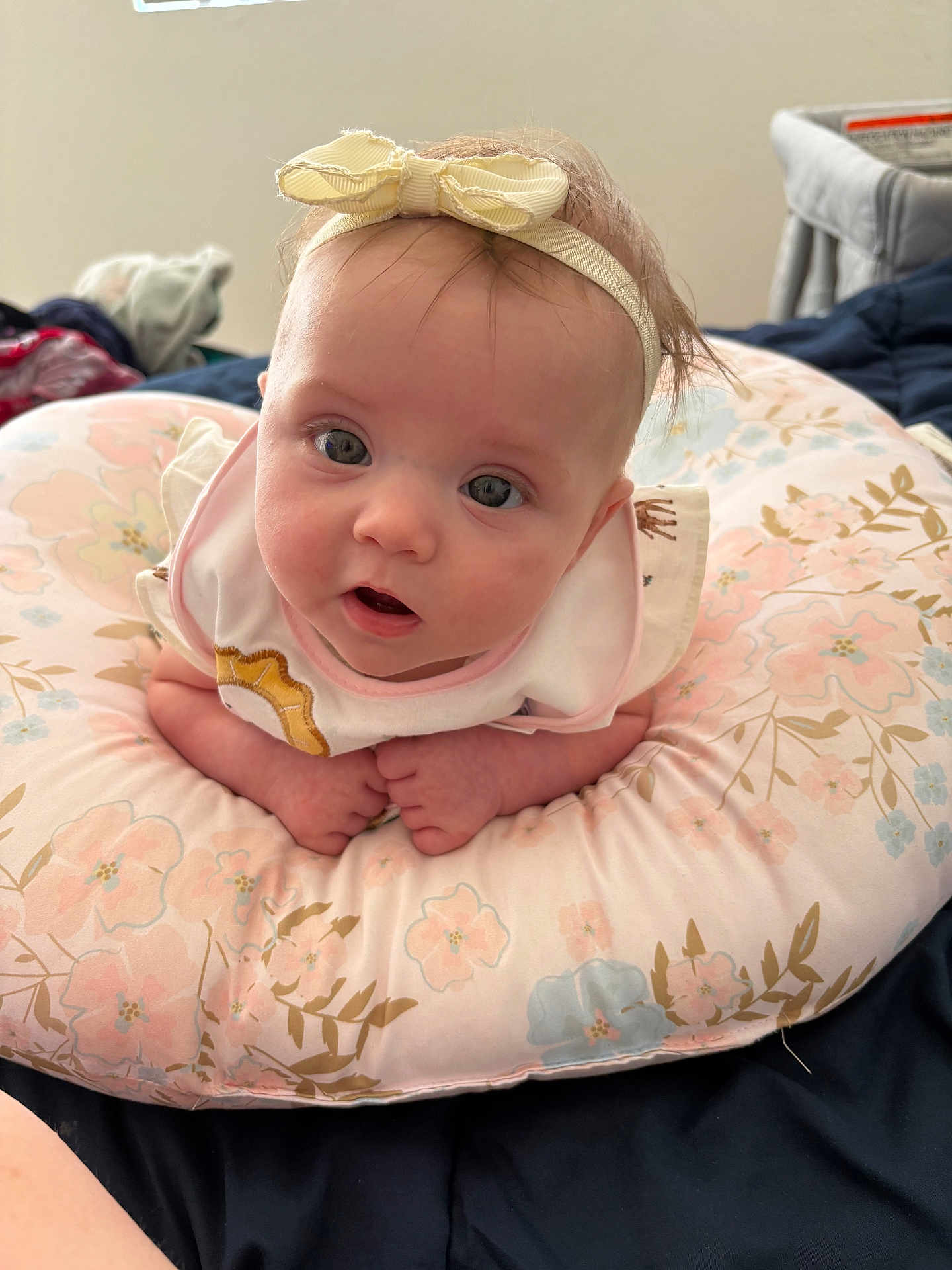 Cassidy joined the competition — help win amazing prizes! baby, headband, bow, cushion, floral_pattern, infant, cute, face, eyes, hands, pink, pastel_colors, bed, blanket, clothing, indoors, portrait, young_child, soft, cozy