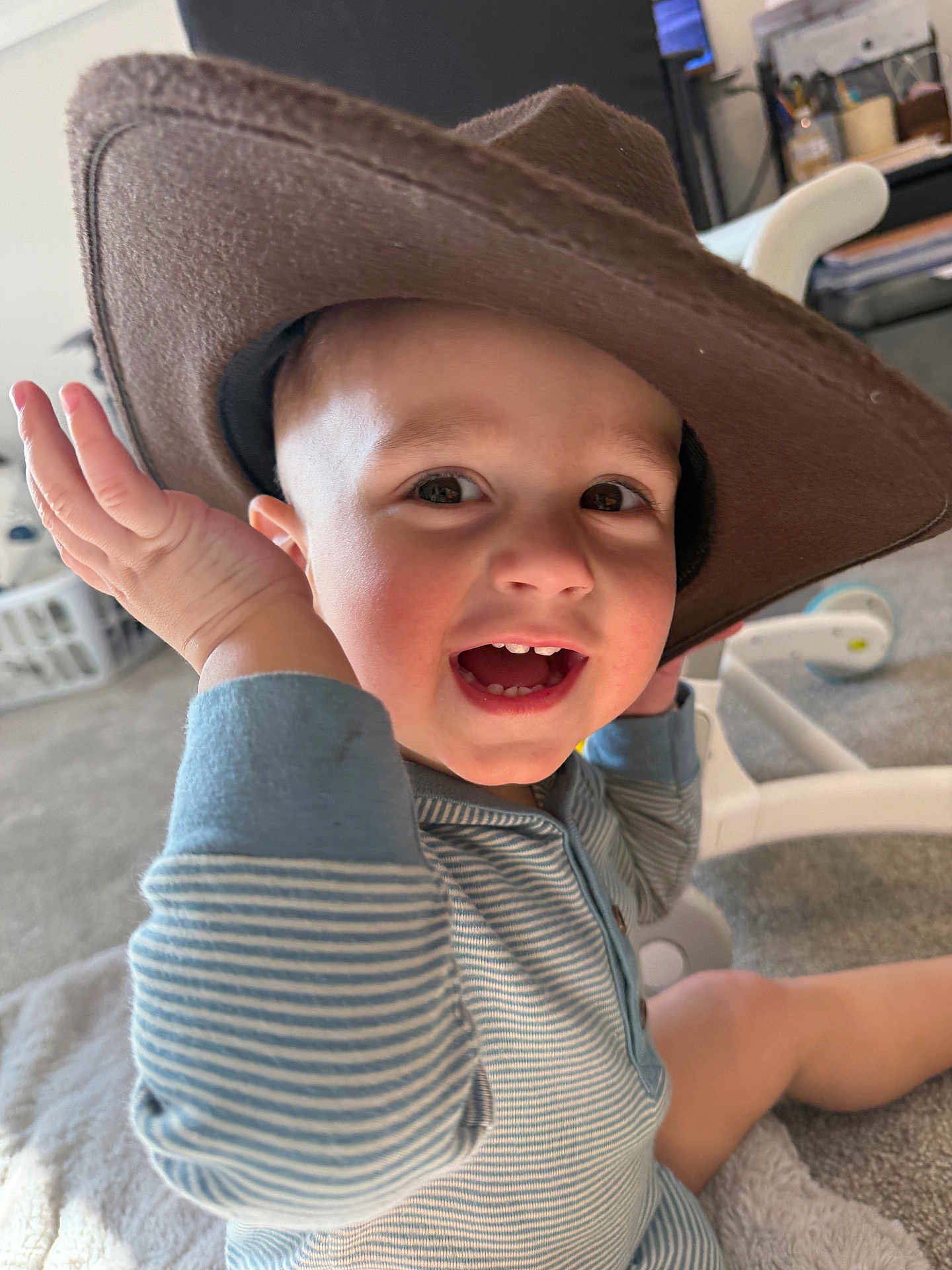 Rhett-Michael joined the competition — help win amazing prizes! toddler, child, smiling, hat, cowboy_hat, onesie, striped_clothing, laughing, teeth, hand, indoor, carpet, blanket, baby_gear, closeup, portrait, playful, happy, seat, home