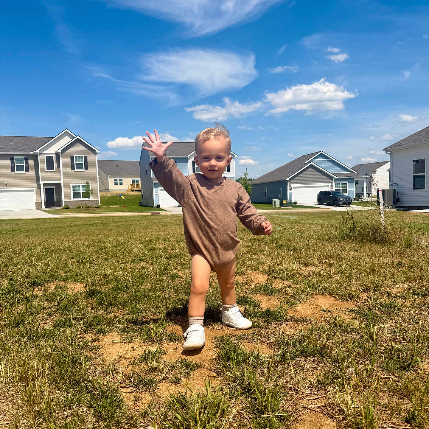 Rhett-Michael joined the competition — help win amazing prizes! toddler, child, grass, field, suburban, houses, blue_sky, clouds, smiling, waving, outdoor, sunny, casual_clothing, young_child, walking, daylight, residential_area, happy, bare_legs, shoes