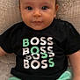 Aaron participe au concours pour gagner de l'argent avec cette photo : baby, child, infant, face, eyes, black_shirt, text_on_clothing, boss_text, green_shorts, blanket, texture, cute, portrait, sitting, indoors, young_child, clothing, comfortable, smiling, relaxed