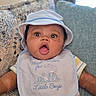 Idris is registered to the contest to win money with this photo: baby, bib, child, close_up, clothing, couch, cushion, face, hat, indoor, infant, open_mouth, photography, portrait, sitting, smiling, sofa, striped_clothing, surprised, wide_eyed