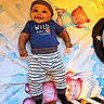 baby, child, infant, smiling, happy, portrait, crib, blanket, star_pattern, teddy_bear, striped_clothing, hat, blue_shirt, black_socks, lying_down, indoor, nursery, bedroom, colorful, photography