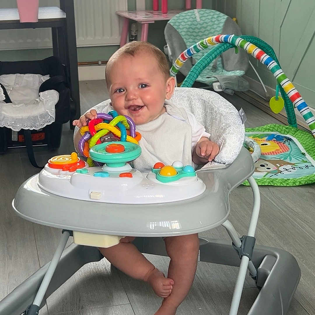 Hunter joined the competition — help win amazing prizes! baby, baby_clothing, baby_toy, baby_walker, chair, child, colorful, floor, flooring, foot, happy, indoor, person, playful, radiator, smile, teddy_bear, toy, walker, window